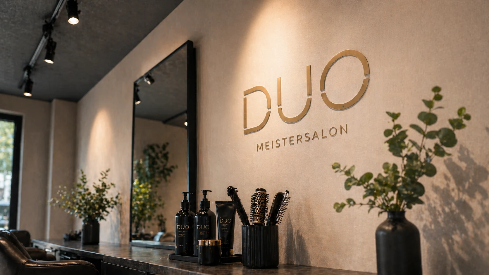 Innenraum des DUO Meistersalon in Hannover mit goldenem Logo, Spiegeln und Friseurprodukten